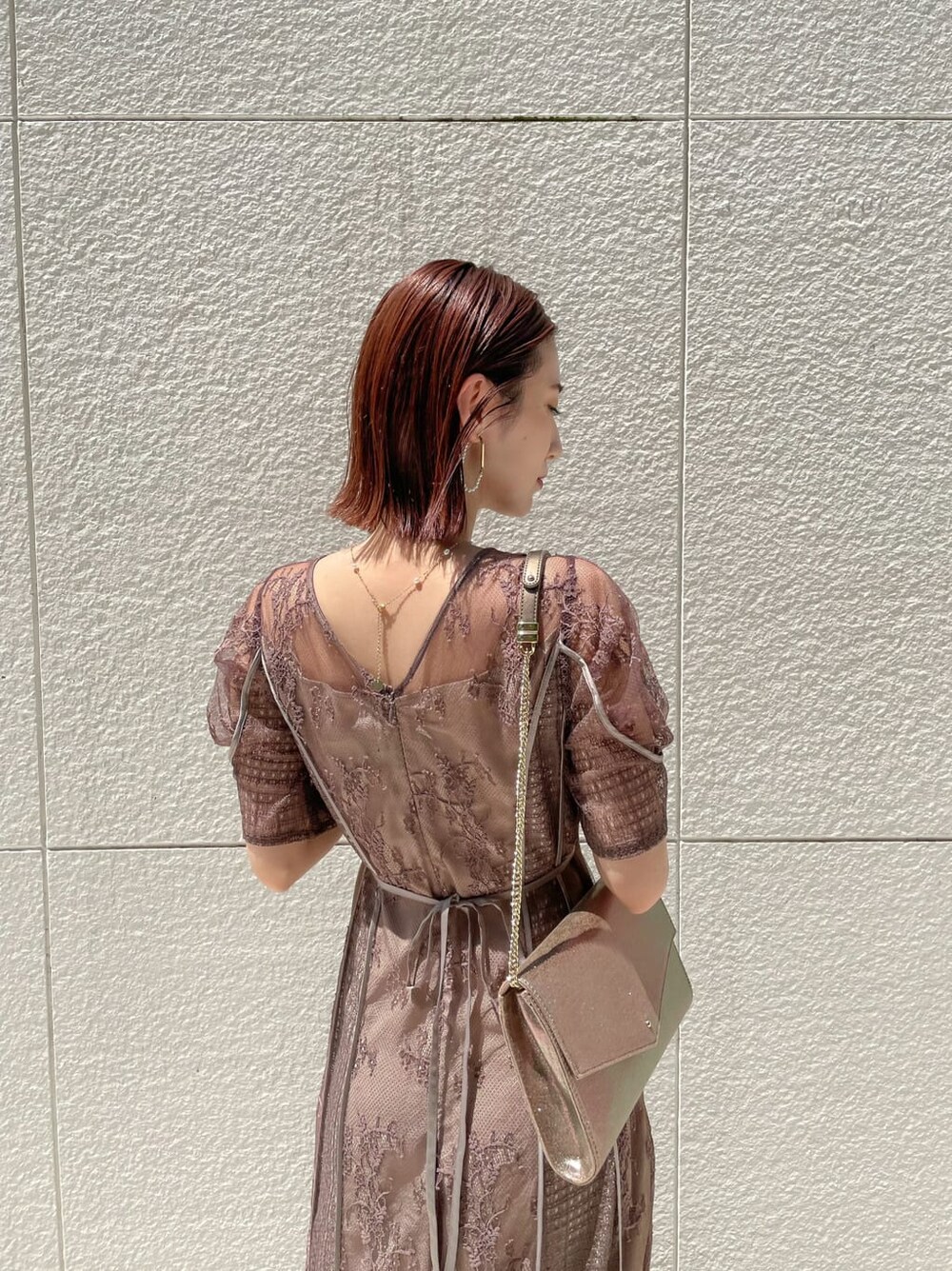 ベージュ系のパンプス、ゴールド系のクラッチバッグ、ベージュ系のドレスを着用したレディースの夏コーディネートの5枚目の写真