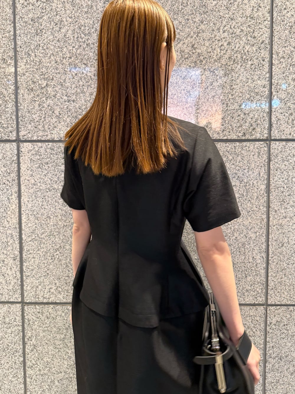 ブラック系のワンピース、ブラック系のハンドバッグを着用したレディースの冬コーディネートの9枚目の写真