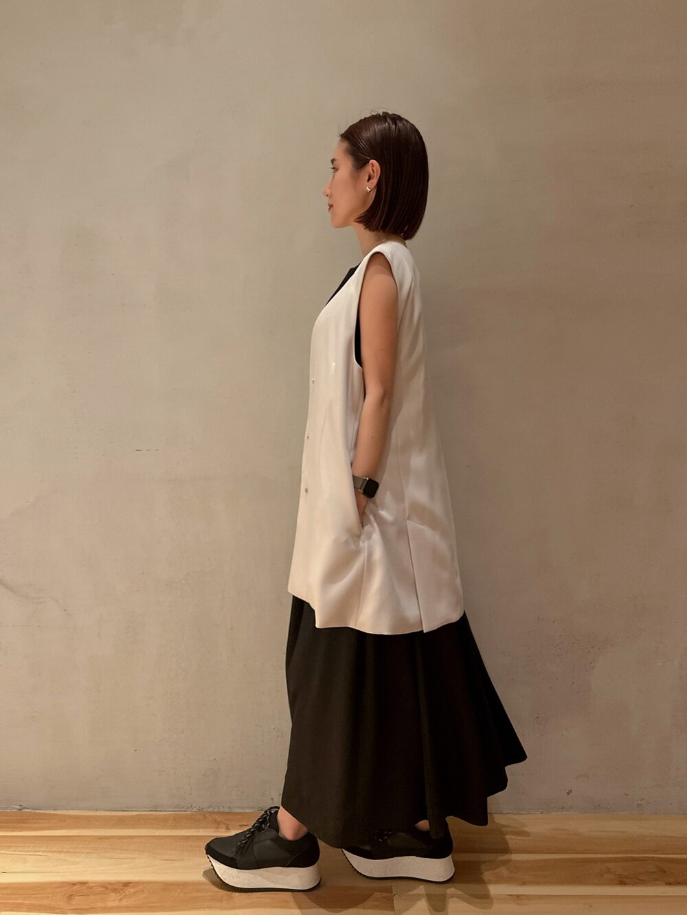 ベージュ系のテーラードジャケット、ブラック系のスニーカー、ブラック系のワンピースを着用したレディースの冬コーディネートの3枚目の写真