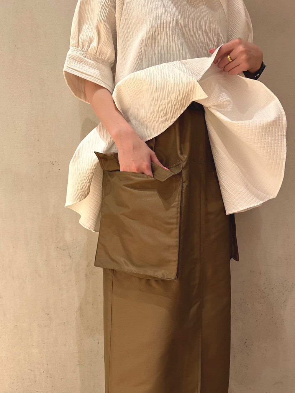 ブラウン系のスカート、ブラック系のスニーカー、ホワイト系のシャツ/ブラウスを着用したレディースの春コーディネートの6枚目の写真