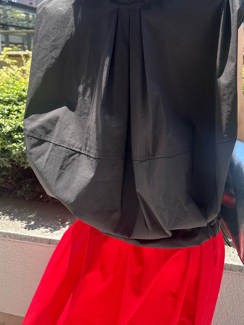 レッド系のスカート、シルバー系のパンプス、シルバー系のトートバッグを着用したレディースの夏コーディネートの7枚目の写真