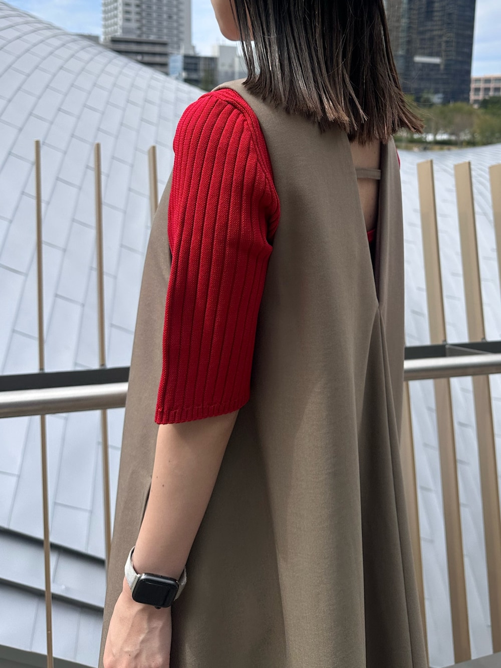 レッド系のニット/セーター、ゴールド系のハンドバッグ、ブラック系のブーツを着用したレディースの秋コーディネートの6枚目の写真