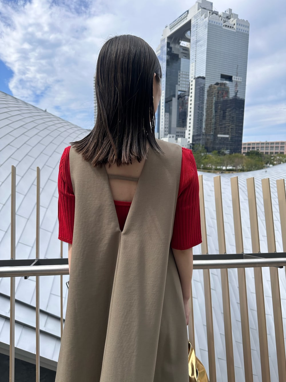 レッド系のニット/セーター、ゴールド系のハンドバッグ、ブラック系のブーツを着用したレディースの秋コーディネートの7枚目の写真