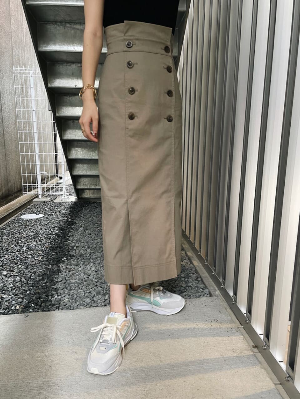 グレー系のスカート、ホワイト系のスニーカー、ブラック系のニット/セーターを着用したレディースの夏コーディネートの3枚目の写真