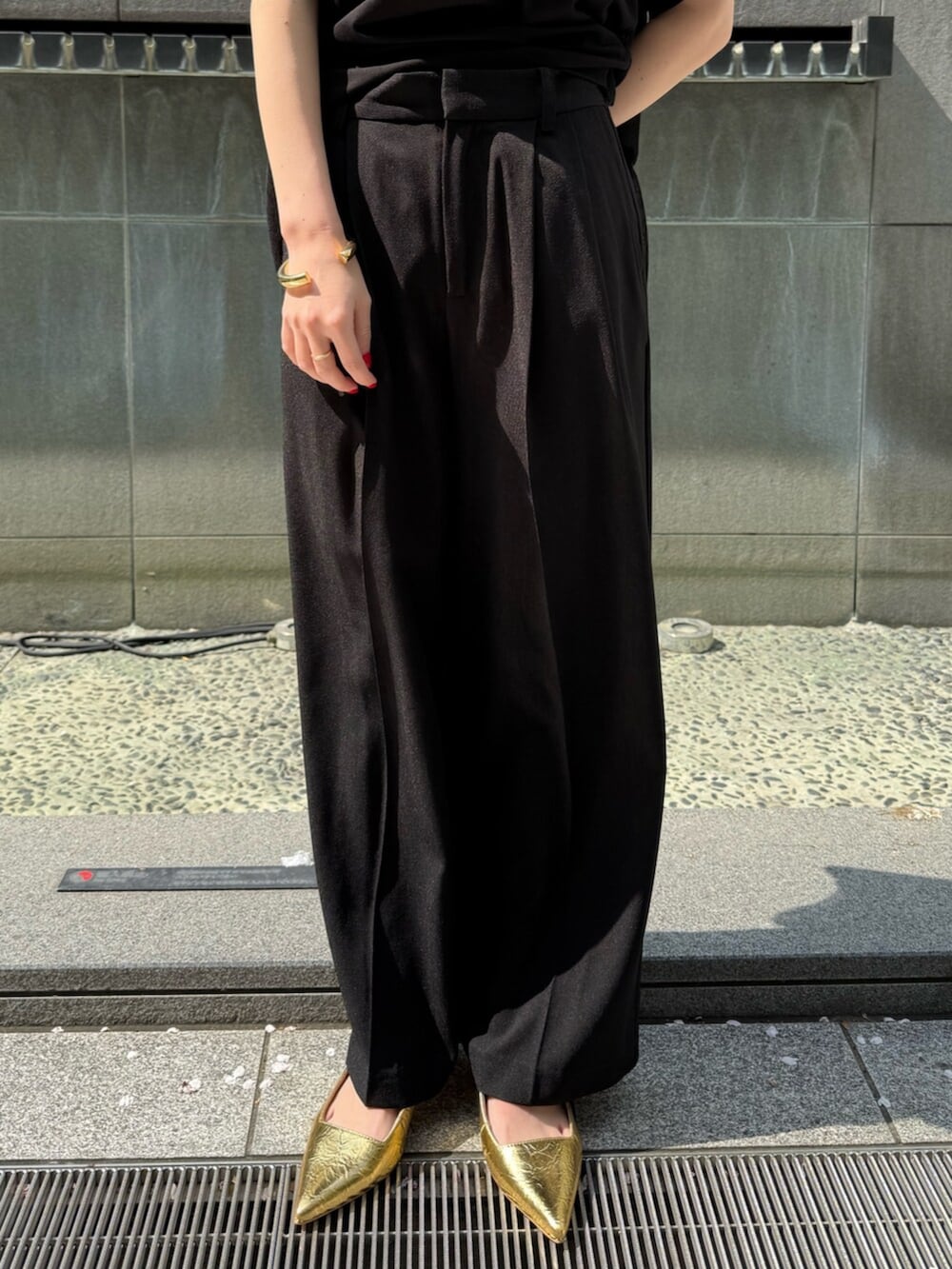 ブラック系のその他パンツ、ゴールド系のサンダル、ホワイト系のTシャツ/カットソーを着用したレディースの春コーディネートの7枚目の写真