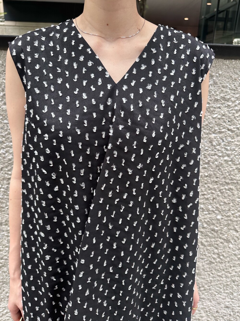 ブラック系のワンピース、ゴールド系のハンドバッグ、ゴールド系のパンプスを着用したレディースの夏コーディネートの6枚目の写真