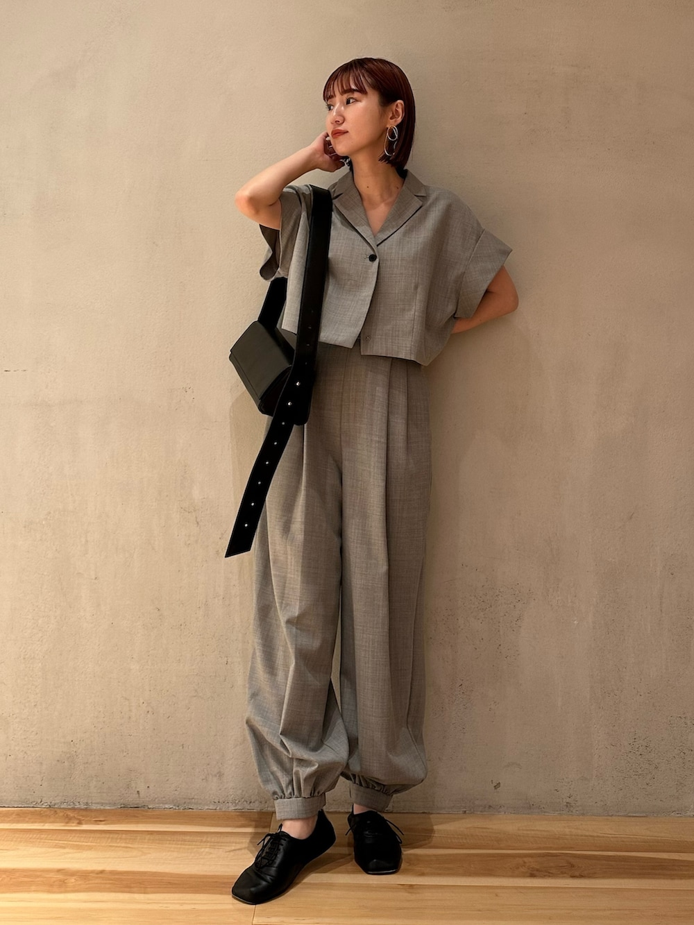 グレー系のテーラードジャケット、ブラック系のショルダーバッグ、ブラック系のバレエシューズを着用したレディースの夏コーディネートの2枚目の写真