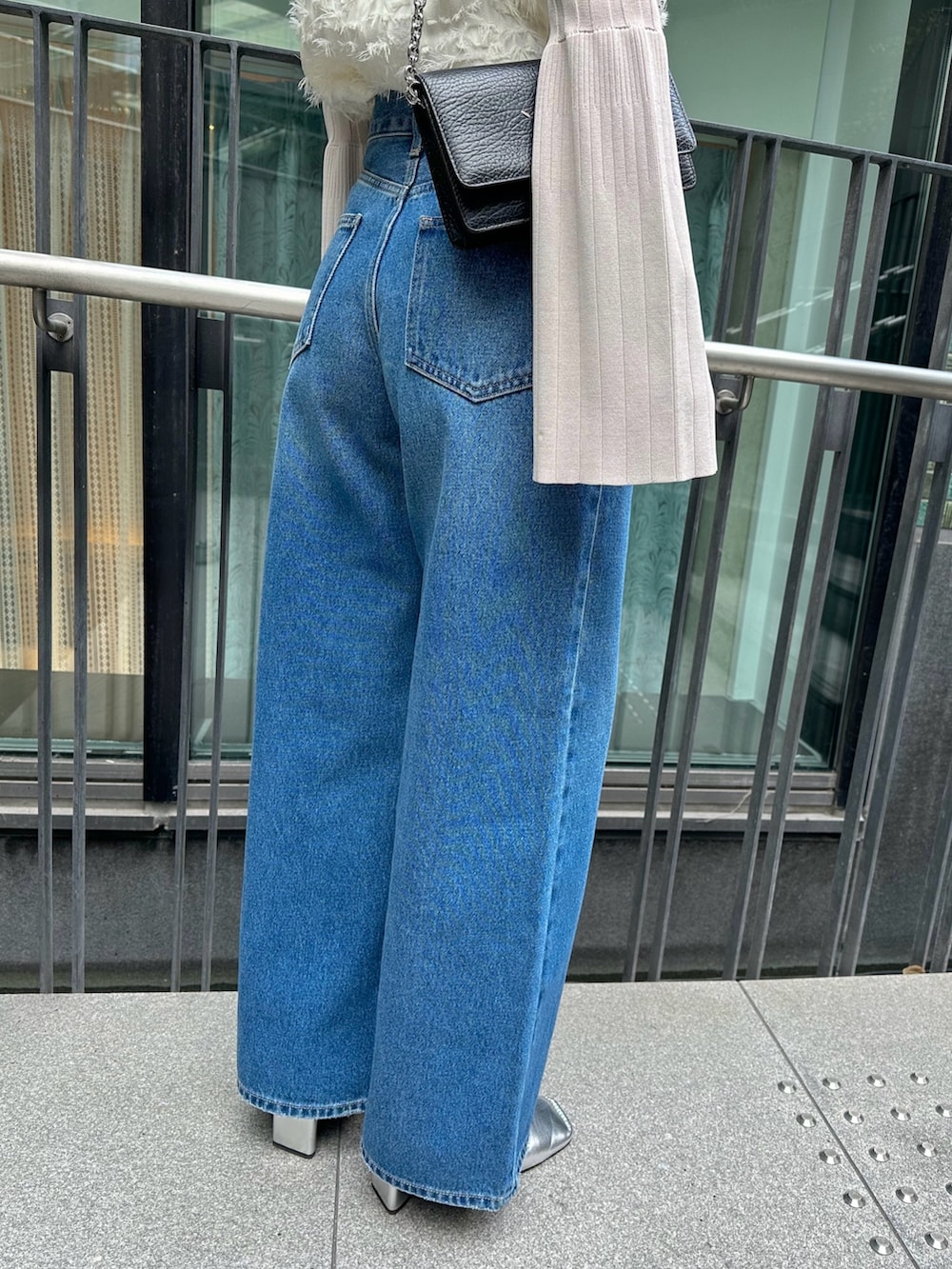 ブルー系のデニムパンツ、ホワイト系のキャミソール、ホワイト系のニット/セーターを着用したレディースの冬コーディネートの3枚目の写真