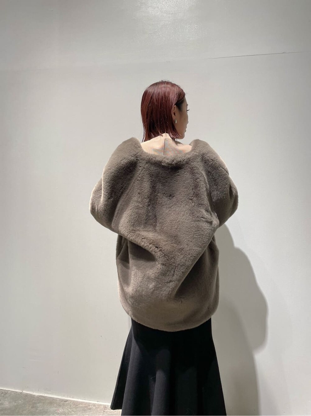 ベージュ系のニット/セーター、ブラウン系のノーカラーコート、ブラック系のブーツを着用したレディースの秋コーディネートの7枚目の写真