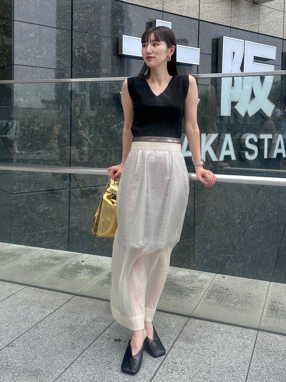 ブラック系のパンプス、ベージュ系のスカート、ブラック系のタンクトップを着用したレディースの夏コーディネートの2枚目の写真