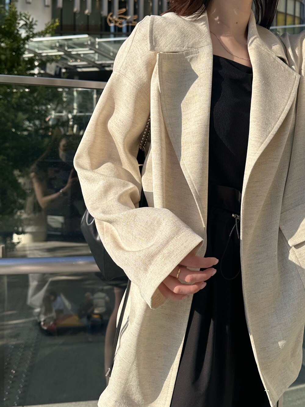 ブラック系のキャミソール、ベージュ系のテーラードジャケット、ブラック系のショルダーバッグを着用したレディースの春コーディネートの7枚目の写真