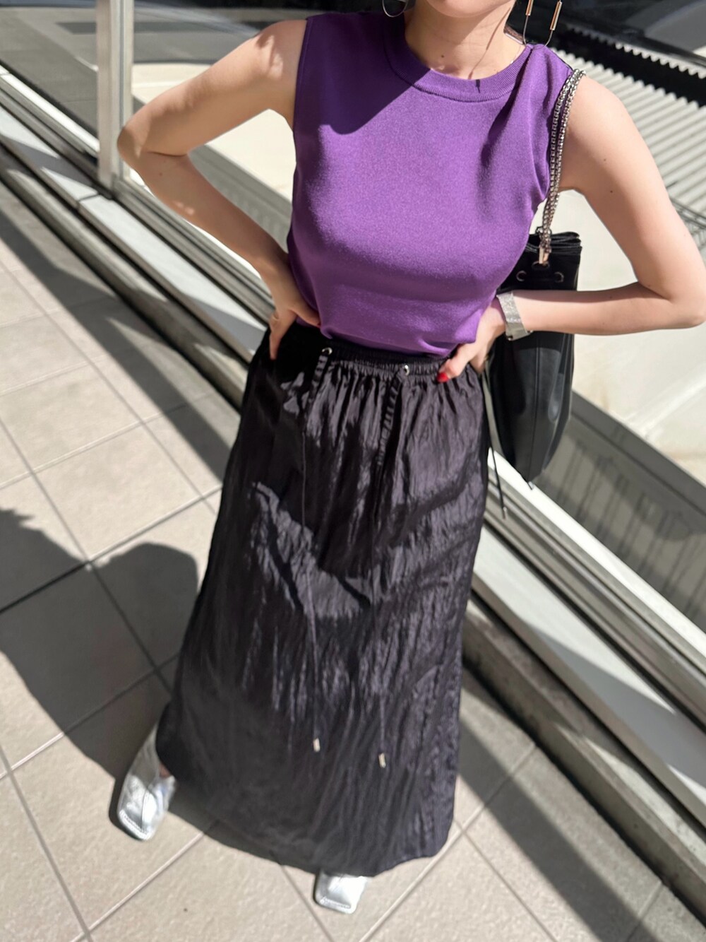 パープル系のニット/セーター、ブルー系のスカート、シルバー系のパンプスを着用したレディースの春コーディネートの4枚目の写真