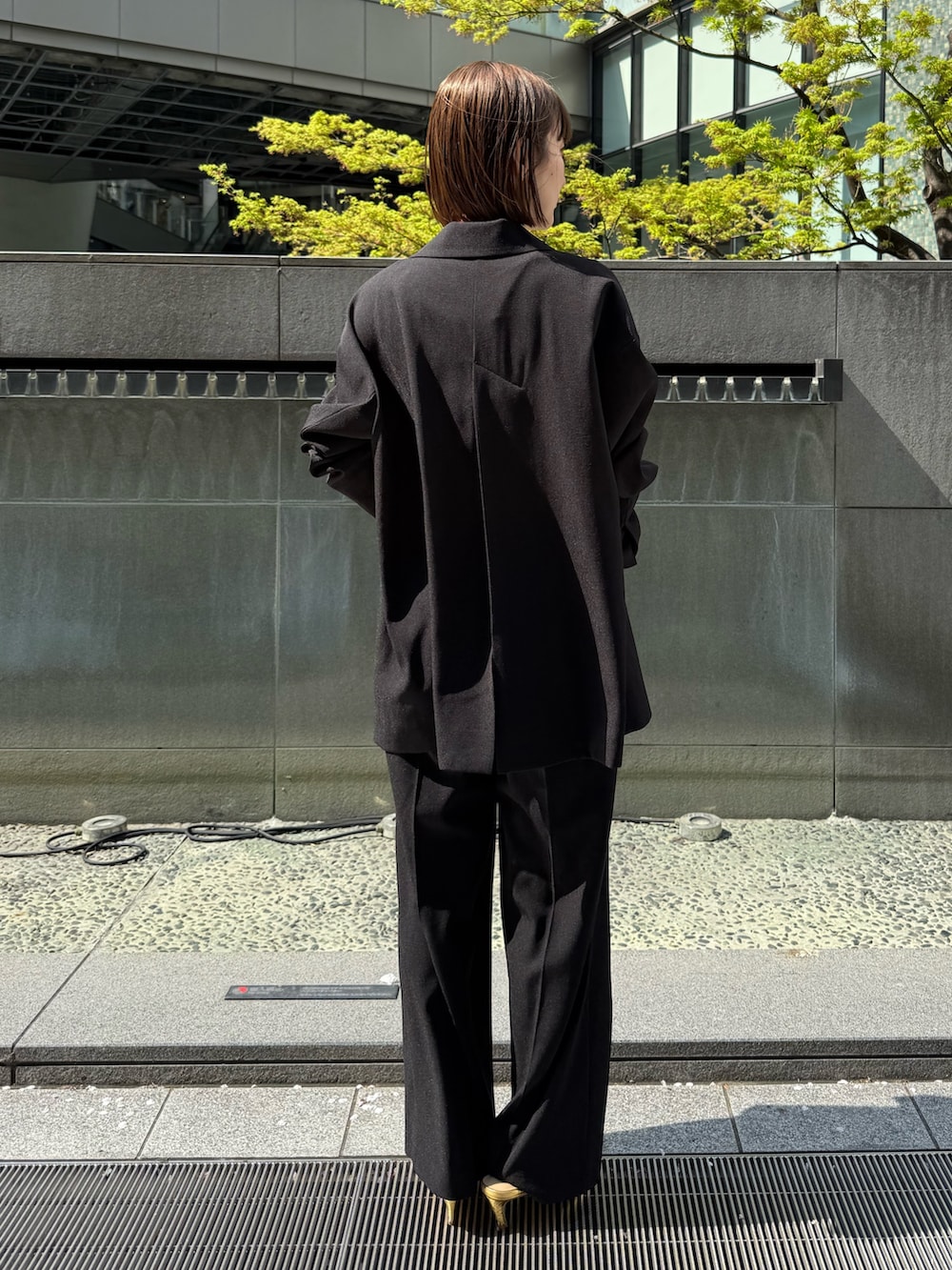 ブラック系のテーラードジャケット、ブラック系のその他パンツ、ゴールド系のサンダルを着用したレディースの春コーディネートの4枚目の写真