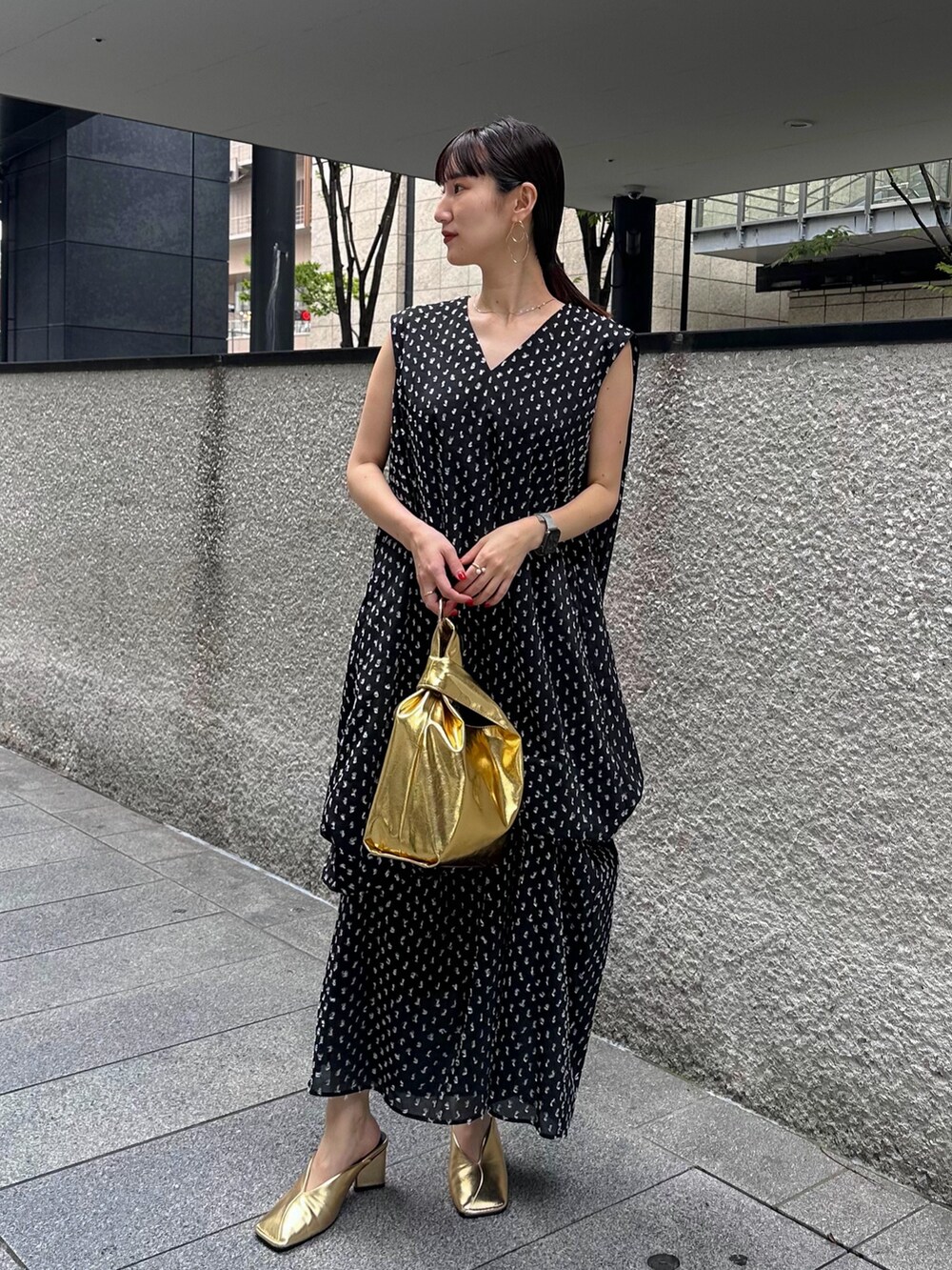 ブラック系のワンピース、ゴールド系のハンドバッグ、ゴールド系のパンプスを着用したレディースの夏コーディネートの2枚目の写真