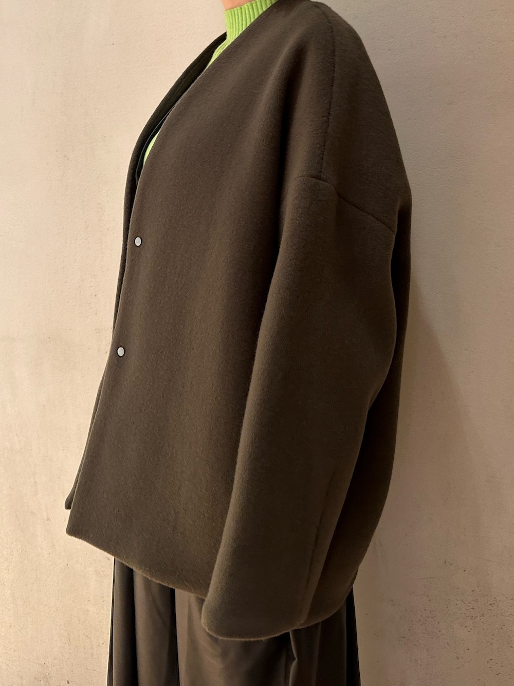 ブラック系のジャンパースカート、ブラック系のブーツ、グリーン系のニット/セーターを着用したレディースの秋コーディネートの8枚目の写真