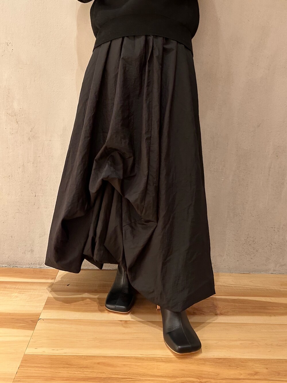 ブラック系のスカート、ブラック系のニット/セーター、ブラック系のブーツを着用したレディースの夏コーディネートの6枚目の写真