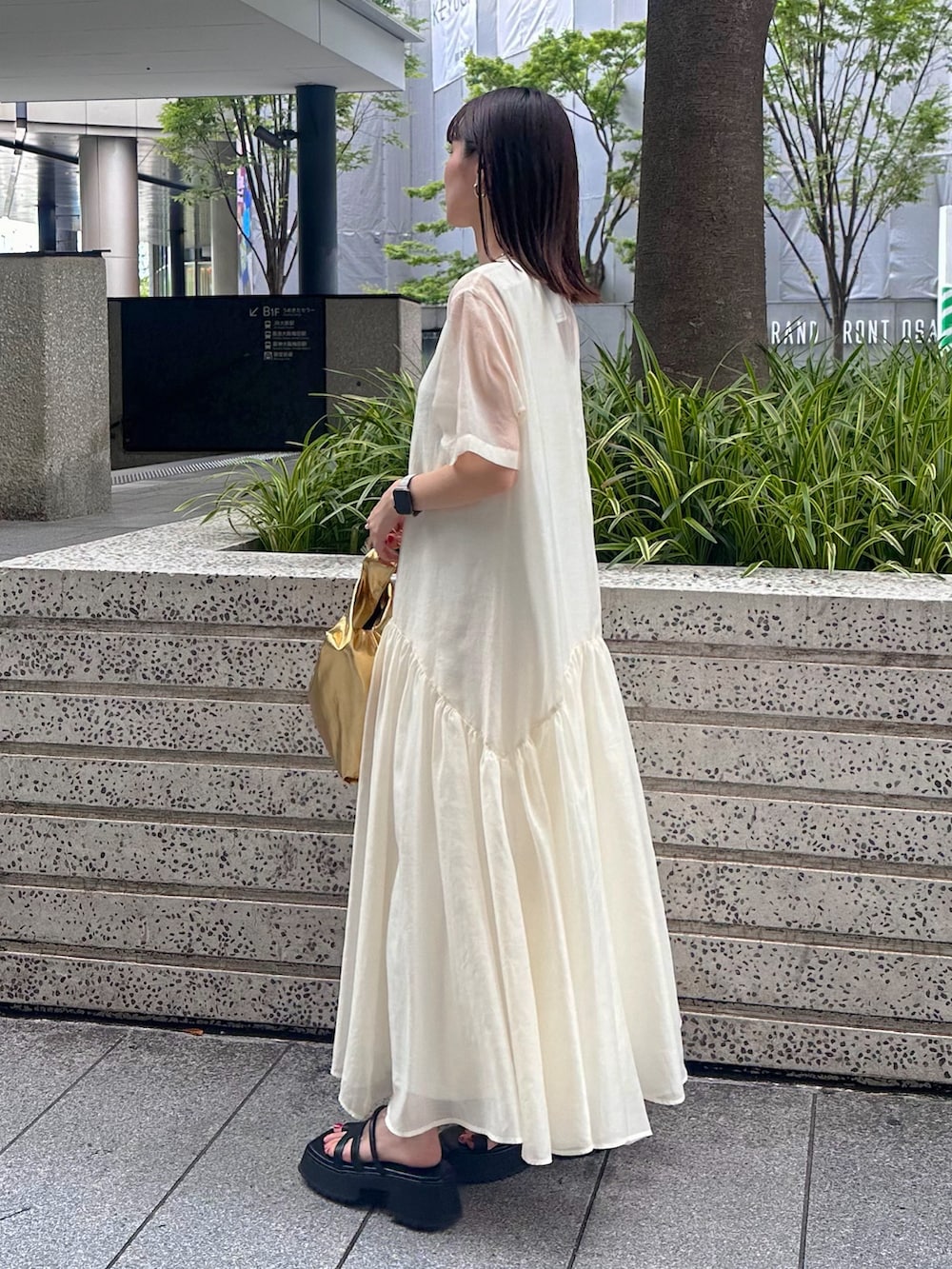 ブラック系のキャミソール、ゴールド系のハンドバッグ、ブラック系のサンダルを着用したレディースの夏コーディネートの3枚目の写真