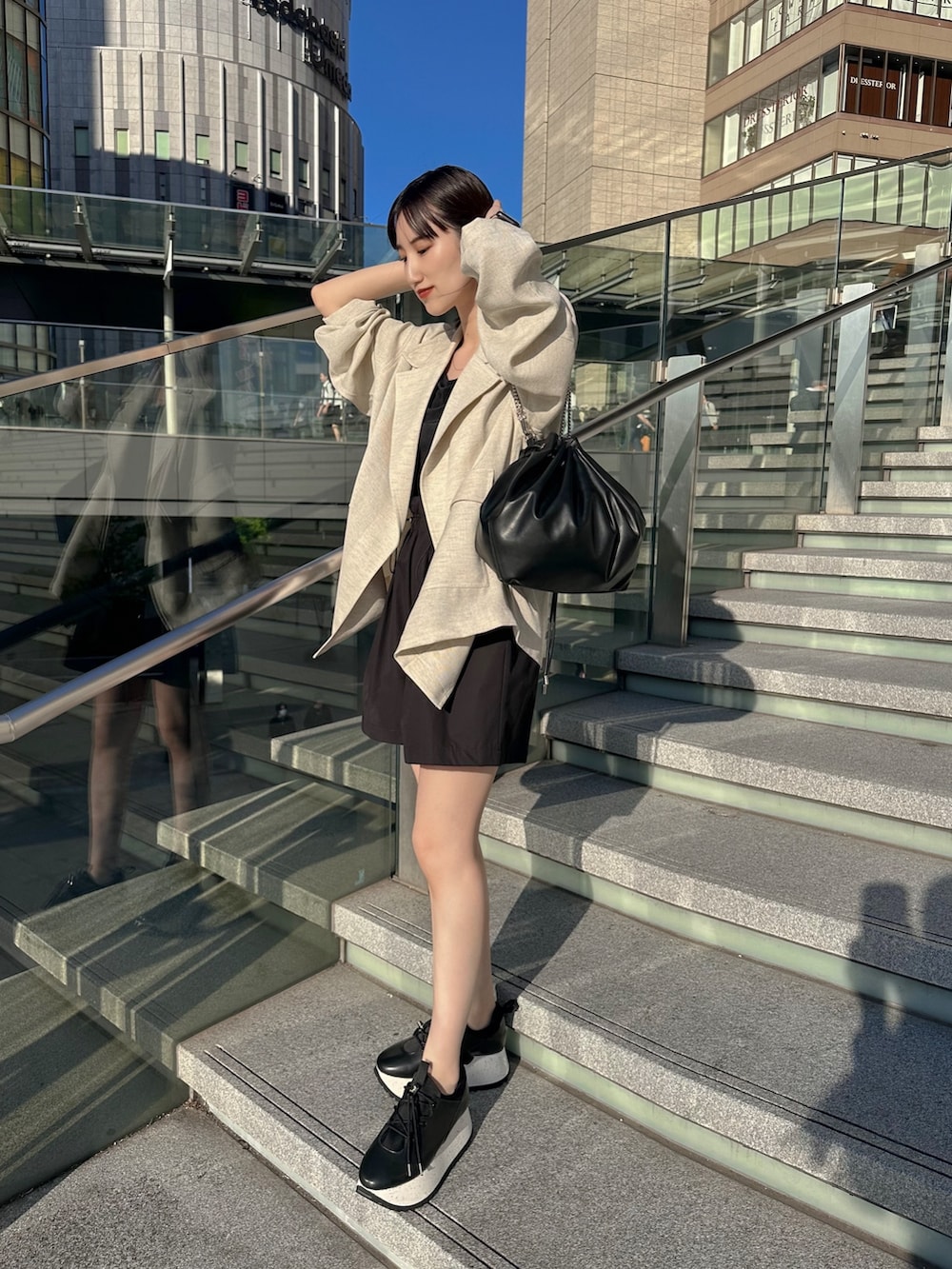 ブラック系のキャミソール、ベージュ系のテーラードジャケット、ブラック系のショルダーバッグを着用したレディースの春コーディネートの3枚目の写真