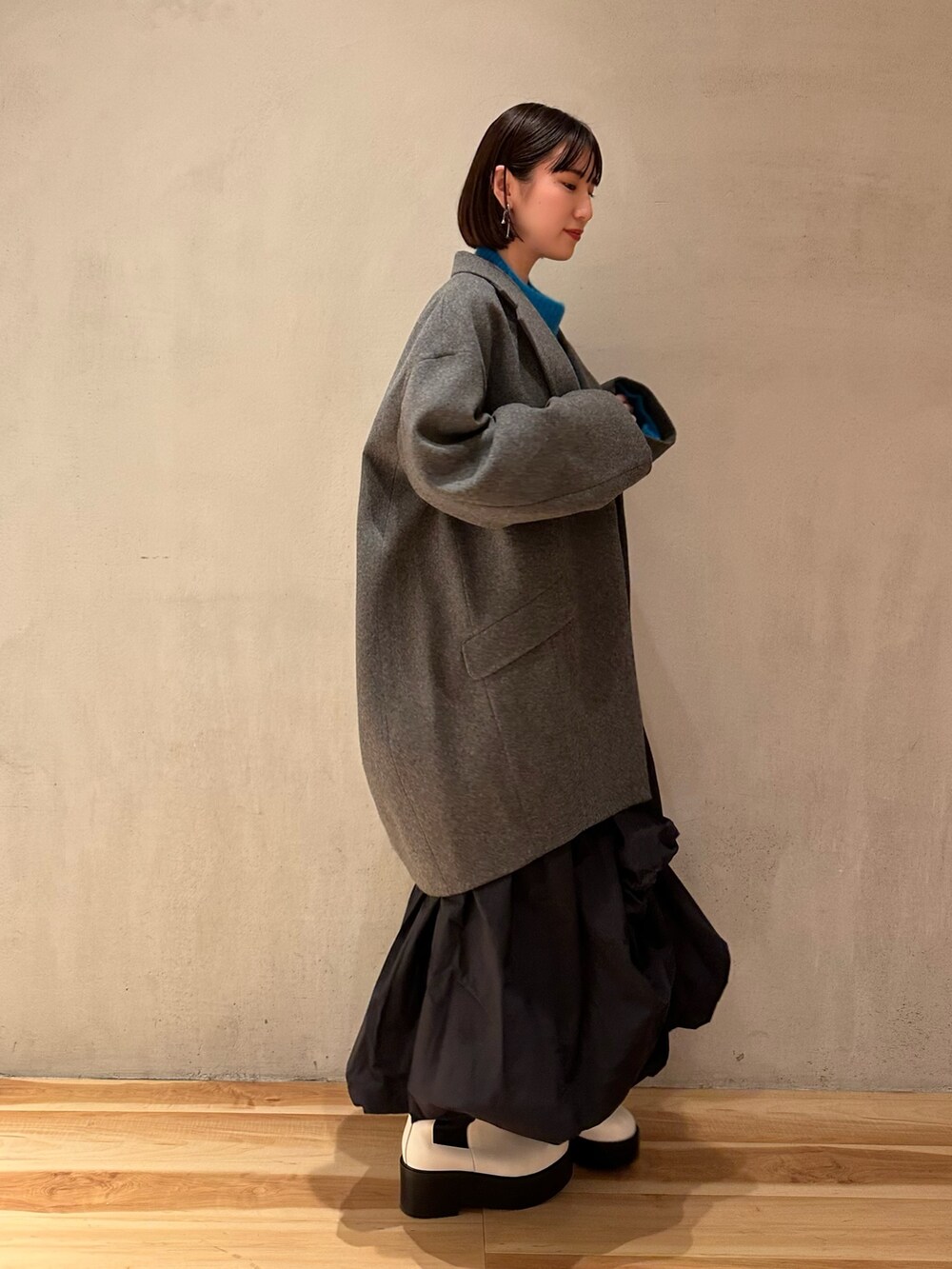 ブラック系のスカート、ブルー系のニット/セーター、ホワイト系のブーツを着用したレディースの冬コーディネートの9枚目の写真