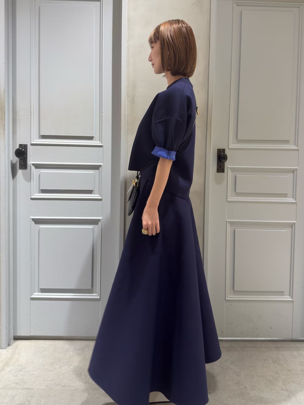 ブルー系のニット/セーター、ブルー系のスカート、ブラック系のスマホグッズを着用したレディースの春コーディネートの3枚目の写真