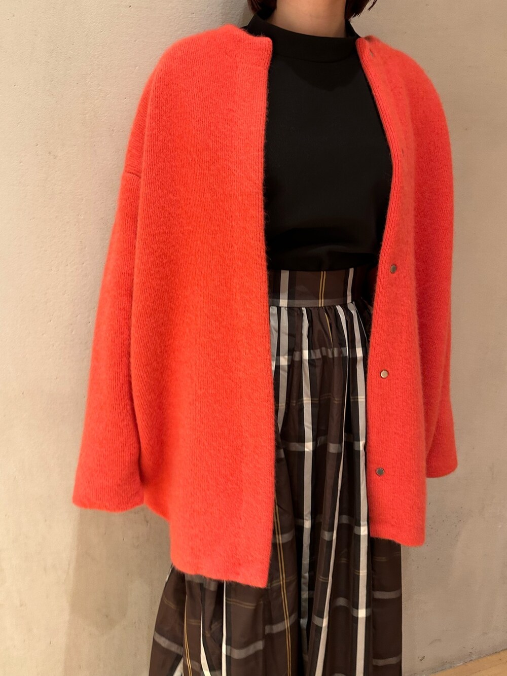 ピンク系のノーカラージャケット、ブラウン系のスカート、ブラック系のブーツを着用したレディースの夏コーディネートの5枚目の写真