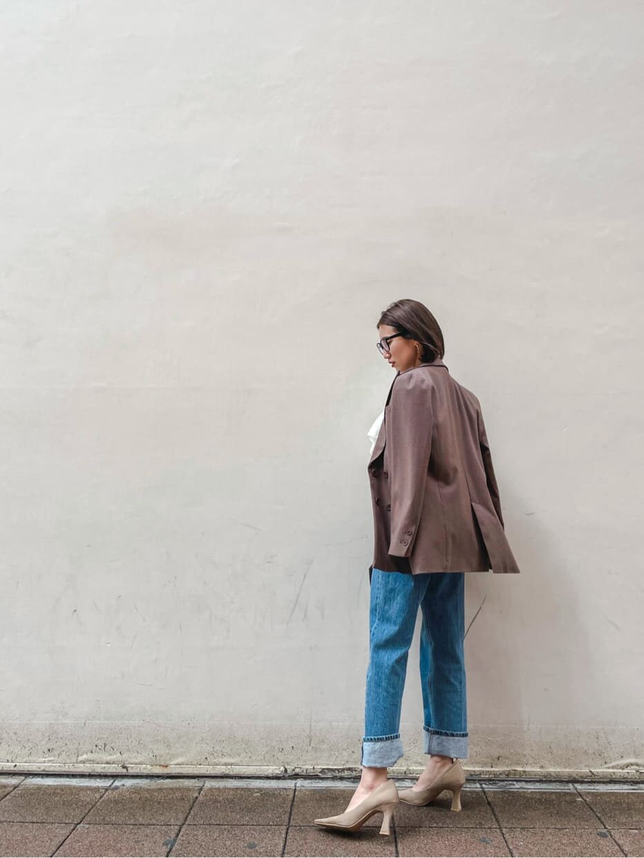 ベージュ系のパンプス、ブラック系のハンドバッグ、ブルー系のデニムパンツを着用したレディースの冬コーディネートの3枚目の写真