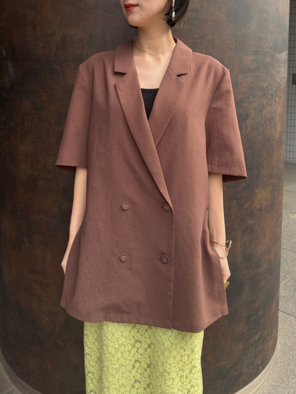 シルバー系のパンプス、ブラウン系のテーラードジャケット、グリーン系のスカートを着用したレディースの春コーディネートの5枚目の写真