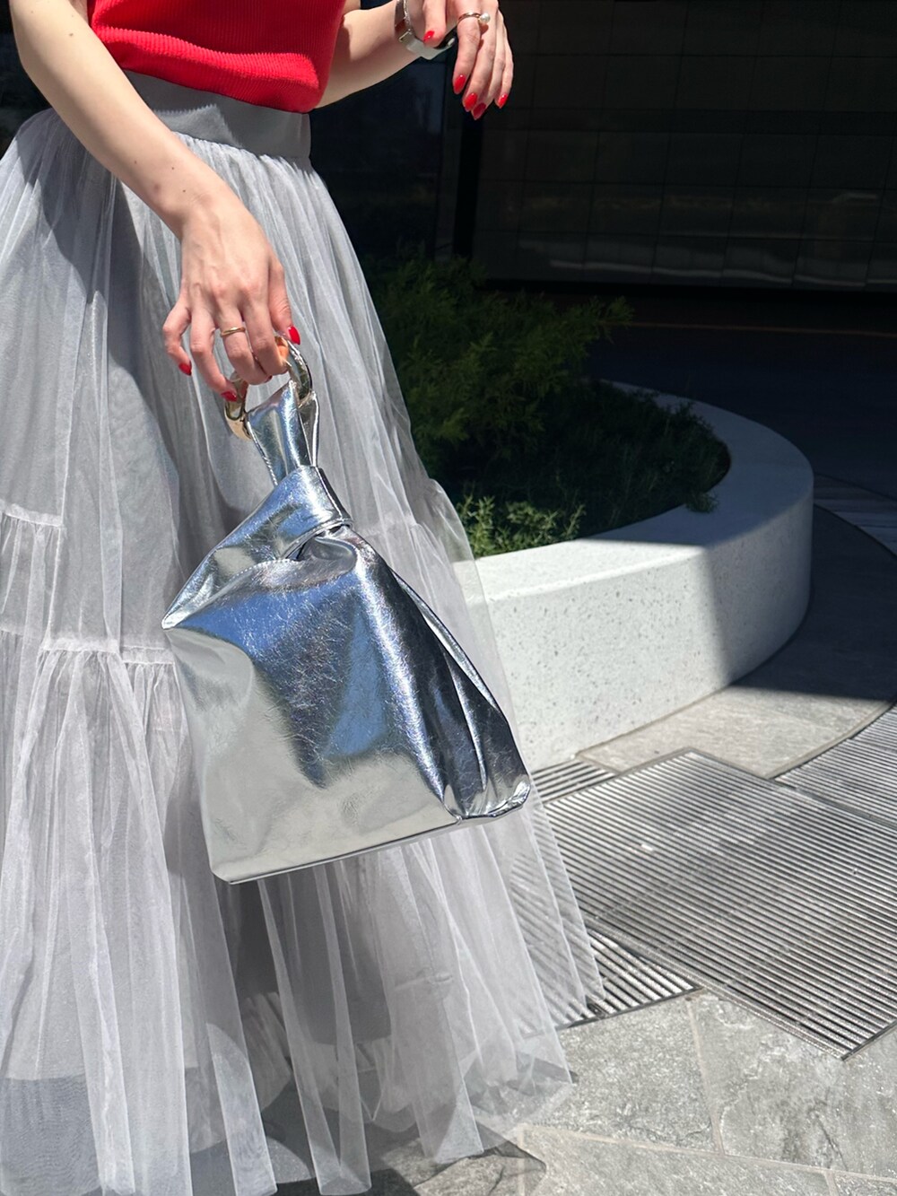 レッド系のタンクトップ、グレー系のスカートを着用したレディースの夏コーディネートの8枚目の写真