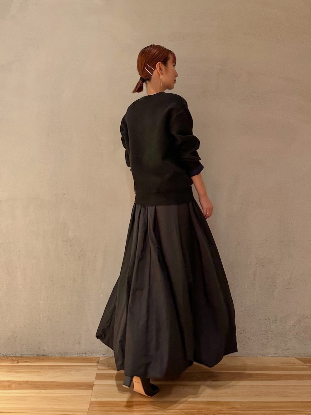 ブラック系のスカート、ブラック系のニット/セーター、ブラック系のブーツを着用したレディースの夏コーディネートの2枚目の写真