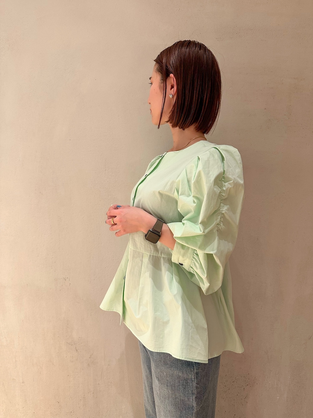 グリーン系のシャツ/ブラウス、ブルー系のデニムパンツ、ホワイト系のスニーカーを着用したレディースの春コーディネートの2枚目の写真