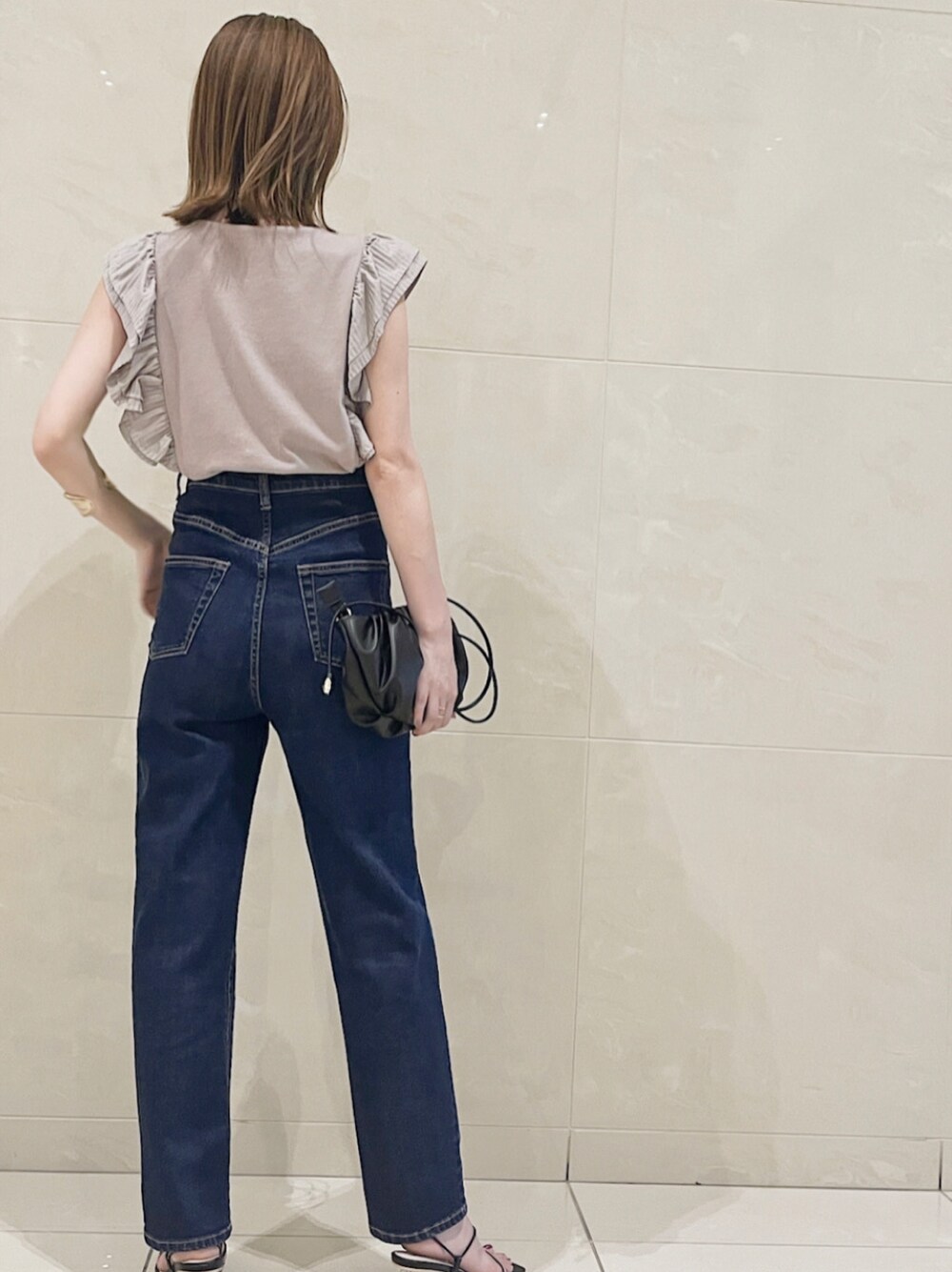 ブルー系のデニムパンツ、ブラック系のハンドバッグ、ブラック系のサンダルを着用したレディースの春コーディネートの6枚目の写真