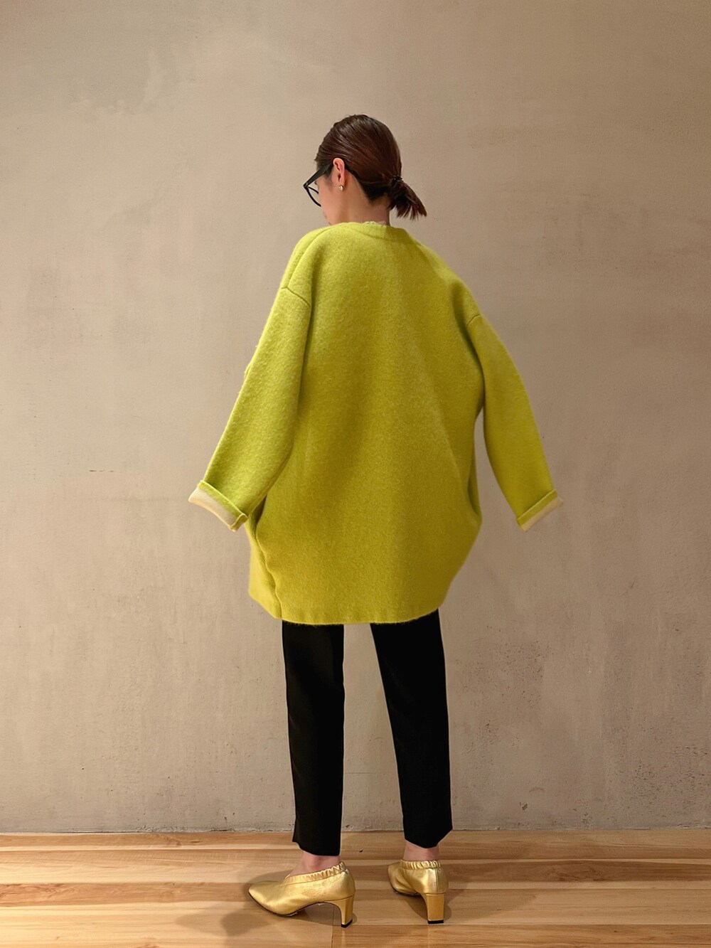 イエロー系のカーディガン/ボレロ、ブラック系のその他パンツ、グリーン系のニット/セーターを着用したレディースの冬コーディネートの3枚目の写真