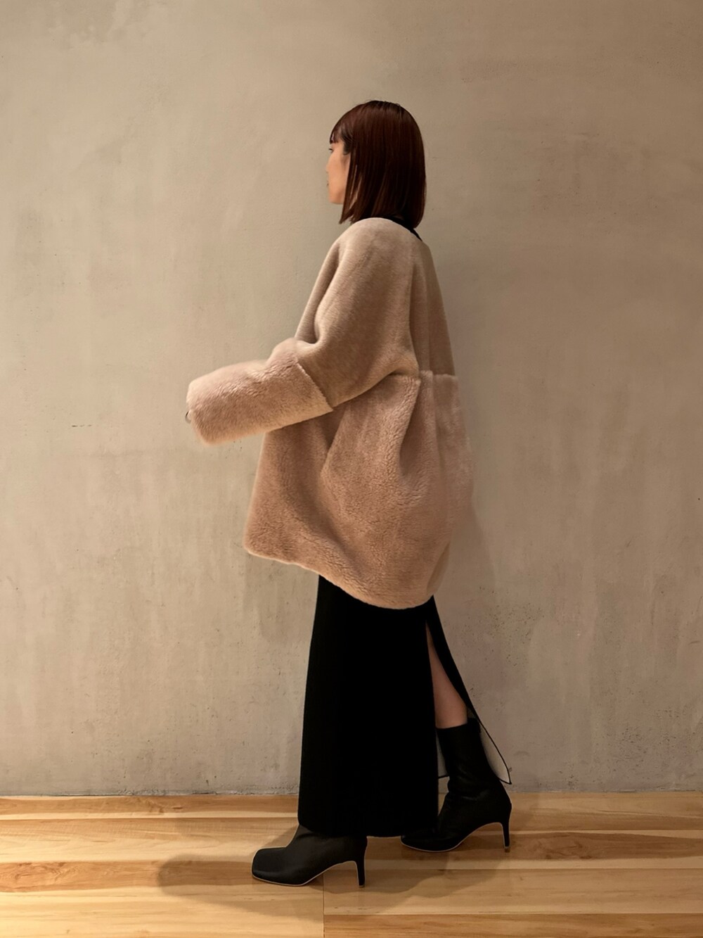 ブラック系のスカート、ブラック系のブーツ、ベージュ系のノーカラーコートを着用したレディースの夏コーディネートの3枚目の写真