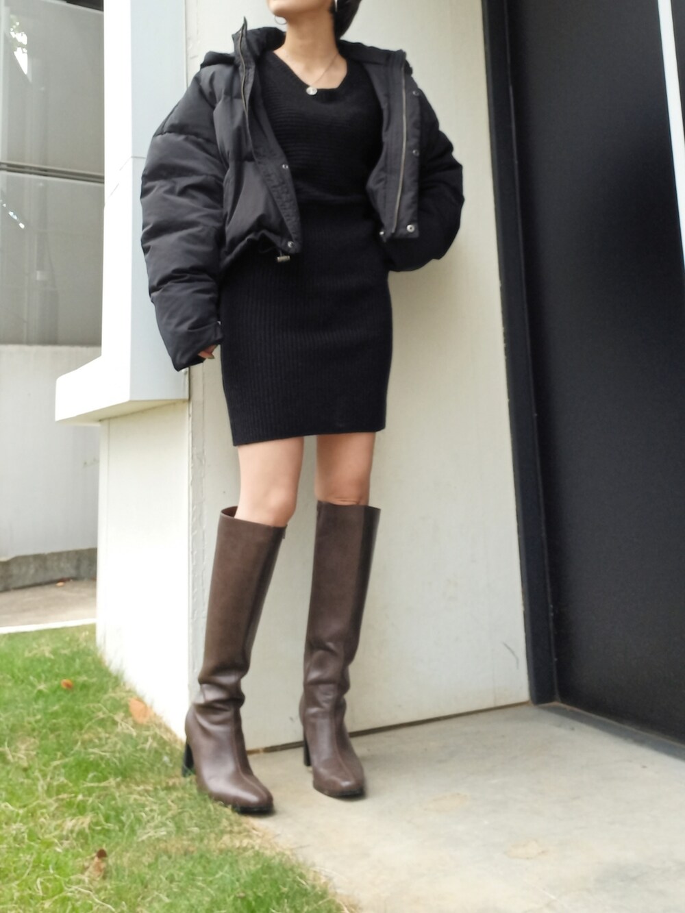 ブラック系のダウンジャケット/コート、ブラック系のワンピース、ブラウン系のブーツを着用したレディースの秋コーディネートの3枚目の写真