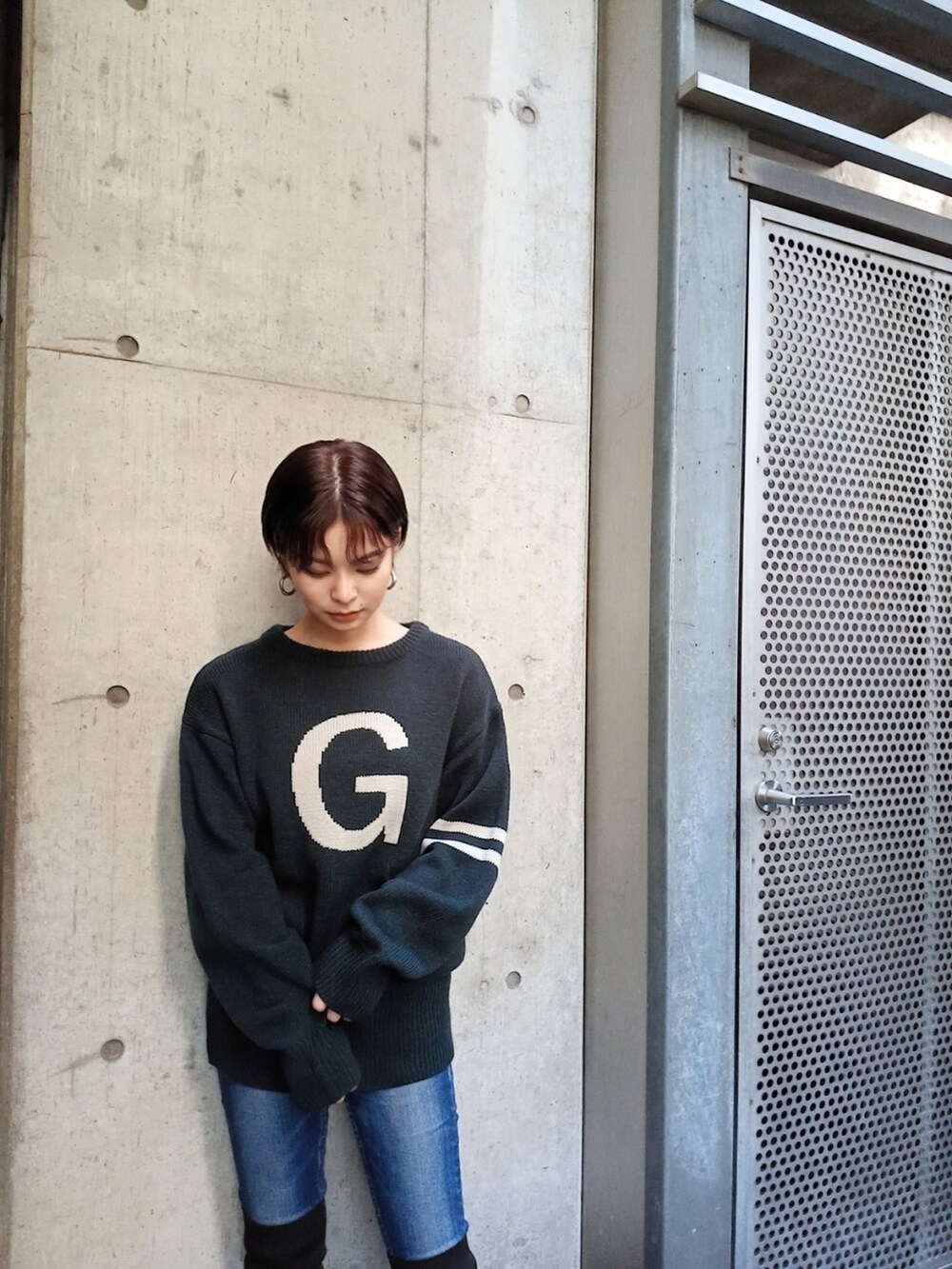 ブルー系のデニムパンツ、ブラック系のブーツ、グリーン系のニット/セーターを着用したレディースの秋コーディネートの2枚目の写真