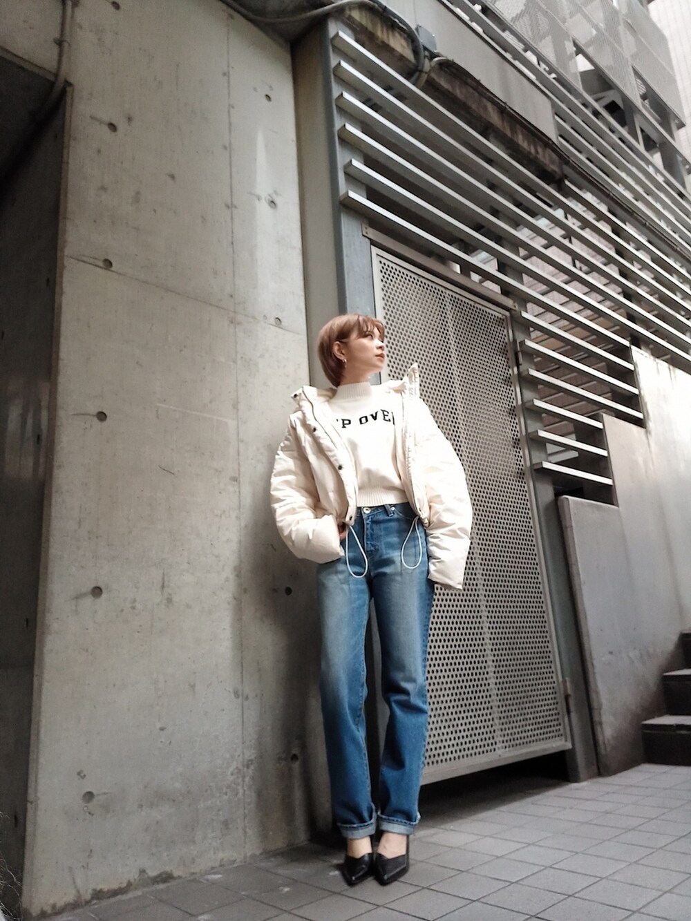 ホワイト系のダウンジャケット/コート、ブルー系のデニムパンツ、ホワイト系のニット/セーターを着用したレディースの秋コーディネートの2枚目の写真