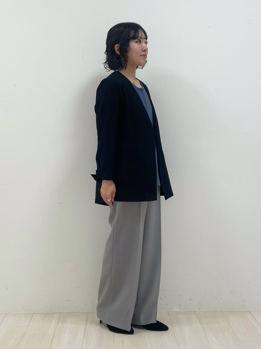 グレー系のスーツパンツ、ブルー系のシャツ/ブラウス、ブラック系のノーカラージャケットを着用したレディースの春コーディネートの2枚目の写真