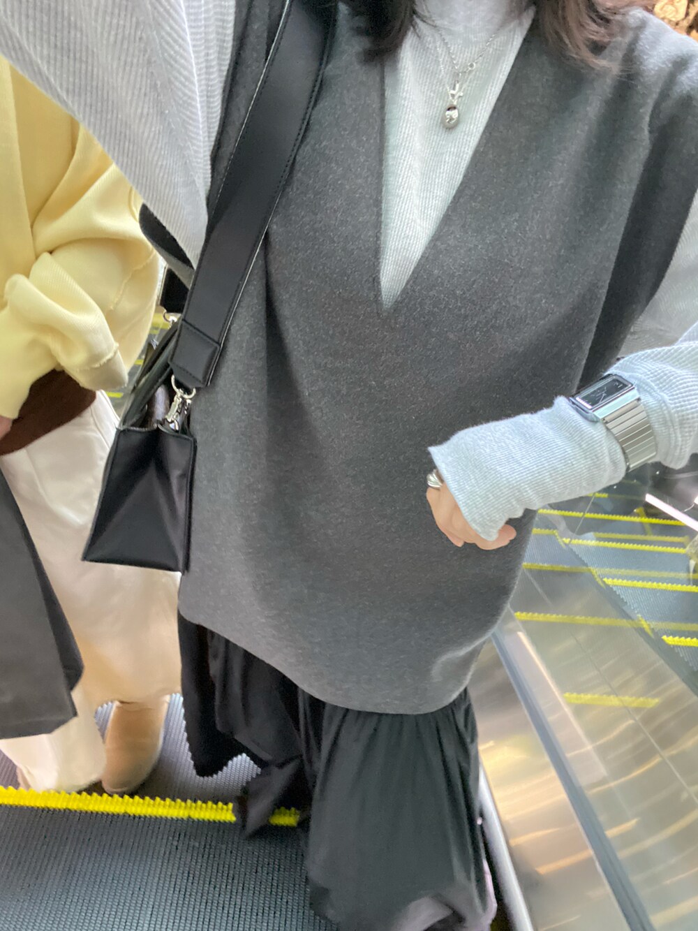 グレー系のTシャツ/カットソー、ブラック系のパンツ、ブラック系のニット/セーターを着用したレディースの秋コーディネートの2枚目の写真