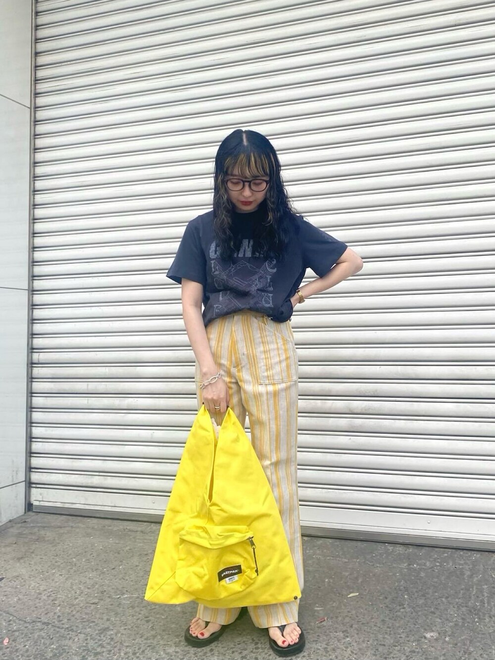 ブラック系のTシャツ/カットソー、イエロー系のその他パンツ、イエロー系のトートバッグを着用したレディースの春コーディネートの2枚目の写真