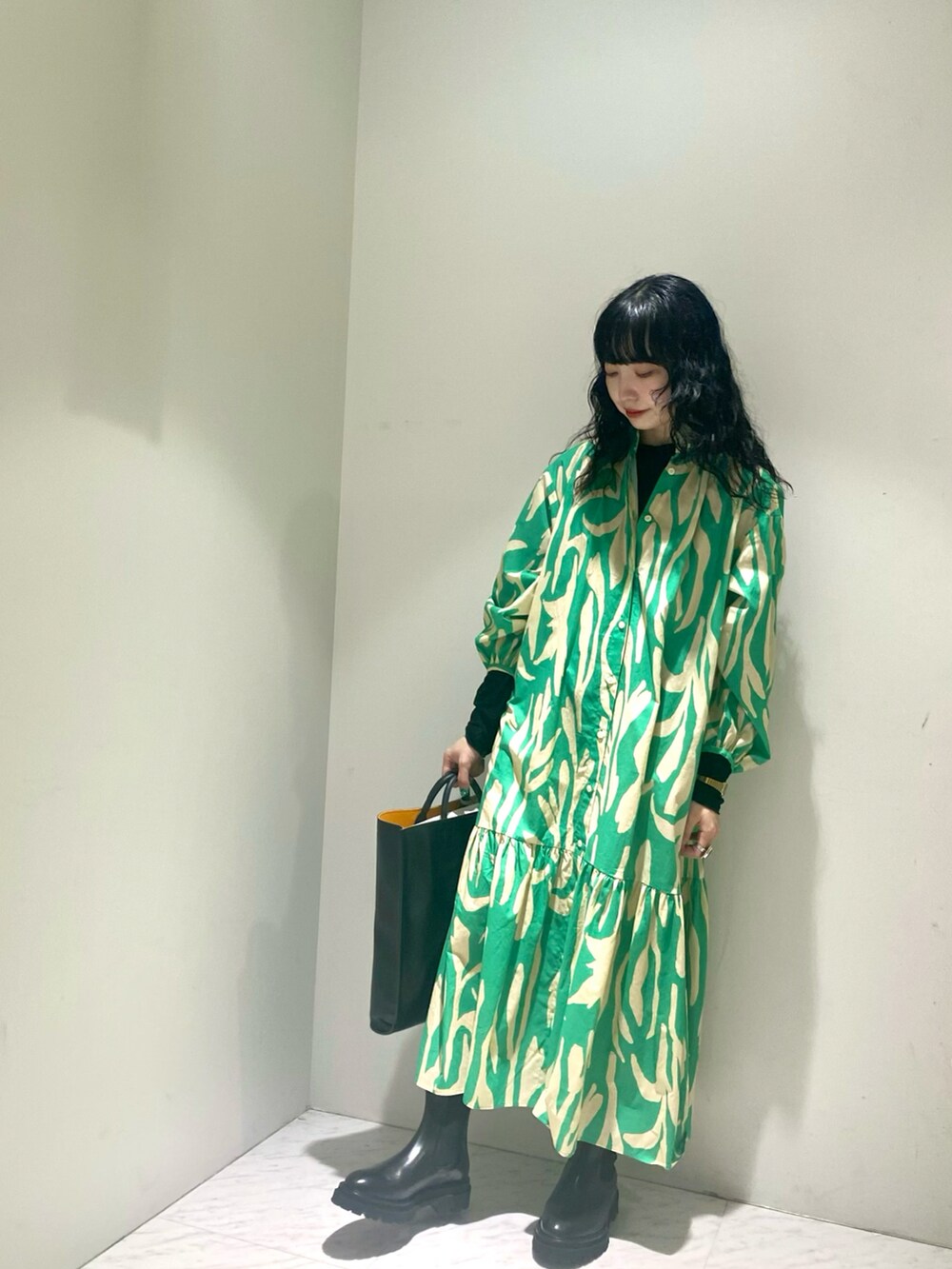 グリーン系のワンピース、ブラック系のブーツ、ブラック系のトートバッグを着用したレディースの冬コーディネートの2枚目の写真