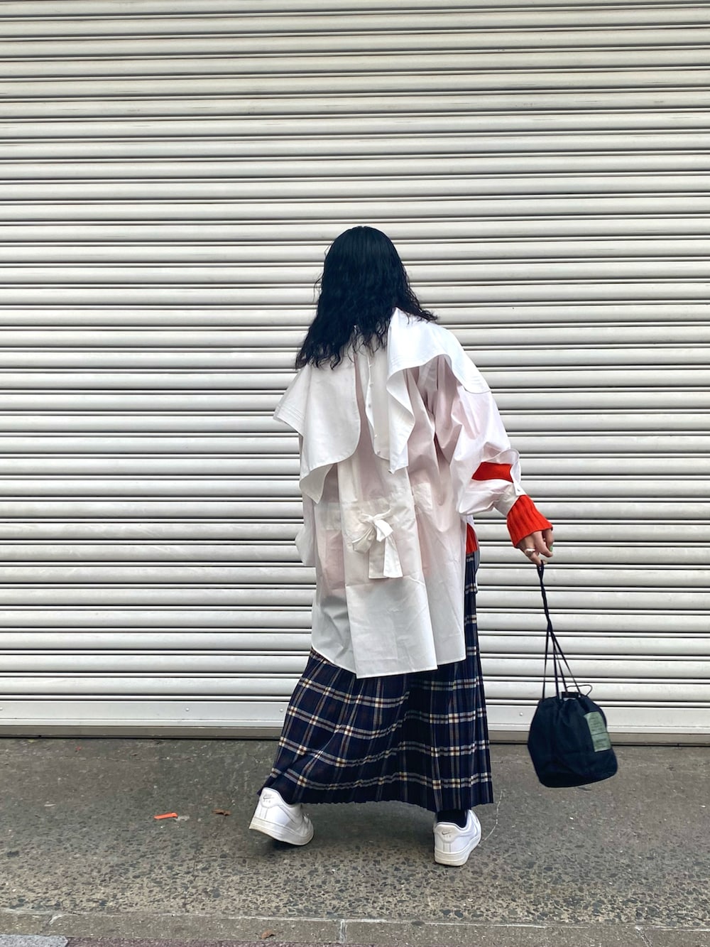 オレンジ系のニット/セーター、ホワイト系のシャツ/ブラウス、ブルー系のスカートを着用したレディースの冬コーディネートの2枚目の写真