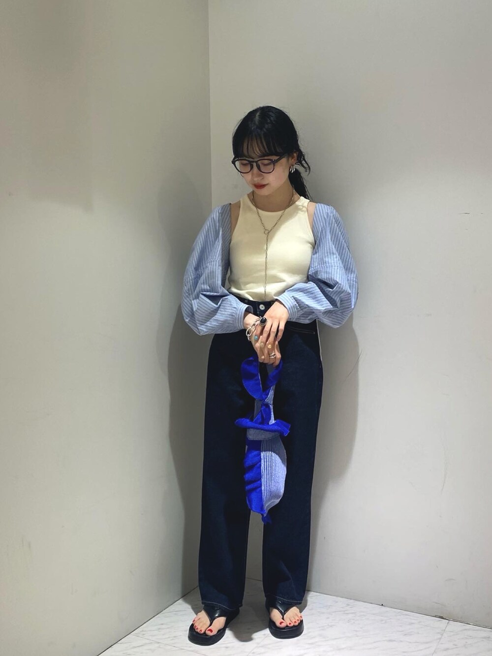 ホワイト系のタンクトップ、ブルー系のデニムパンツ、ブラック系のサンダルを着用したレディースの春コーディネートの2枚目の写真