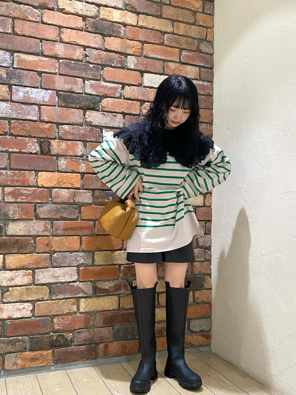 グリーン系のTシャツ/カットソー、イエロー系のハンドバッグ、ブラック系のブーツを着用したレディースの冬コーディネートの2枚目の写真