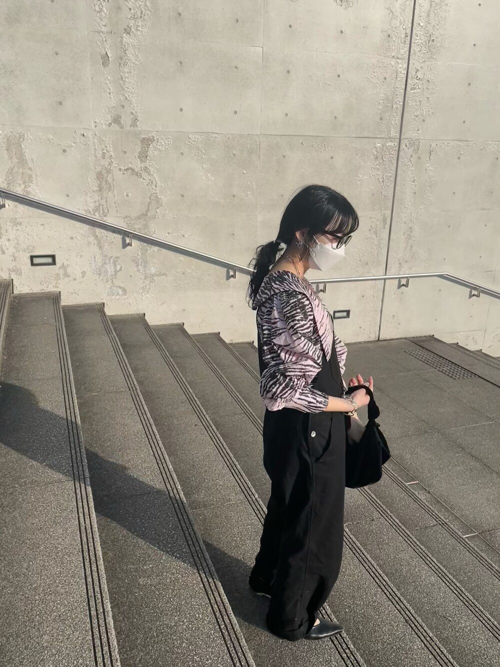 ピンク系のトップス、ブラック系のサロペット/オーバーオール、ブラック系のハンドバッグを着用したレディースの春コーディネートの2枚目の写真