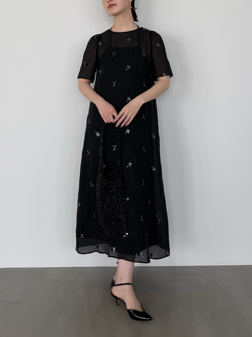 ブラック系のワンピースを着用したレディースの春コーディネートの2枚目の写真