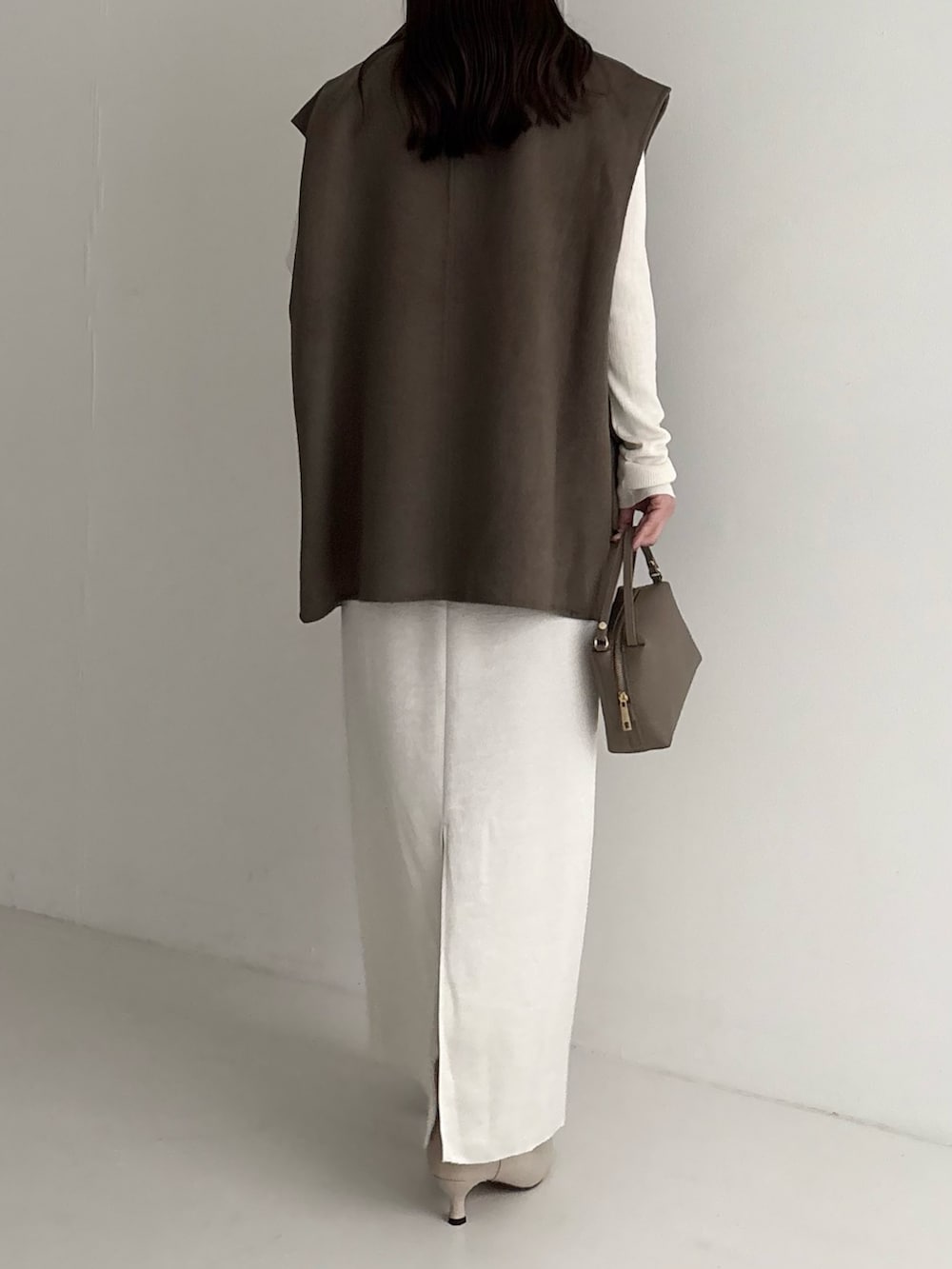 ホワイト系のニット/セーター、グリーン系のその他アウター、ホワイト系のスカートを着用したレディースの秋コーディネートの2枚目の写真