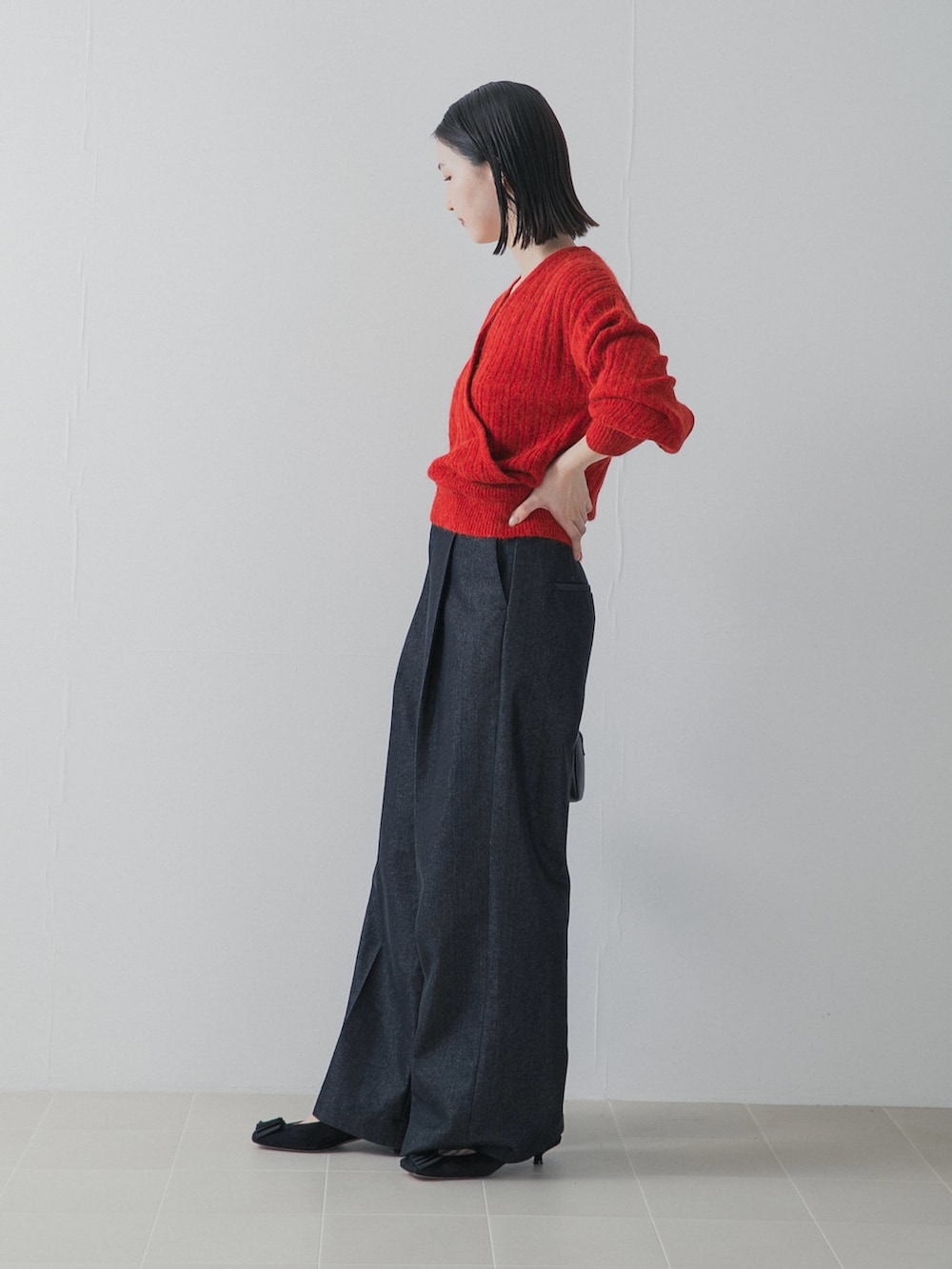 レッド系のニット/セーター、ブルー系のデニムパンツ、ブラック系のハンドバッグを着用したレディースの秋コーディネートの3枚目の写真