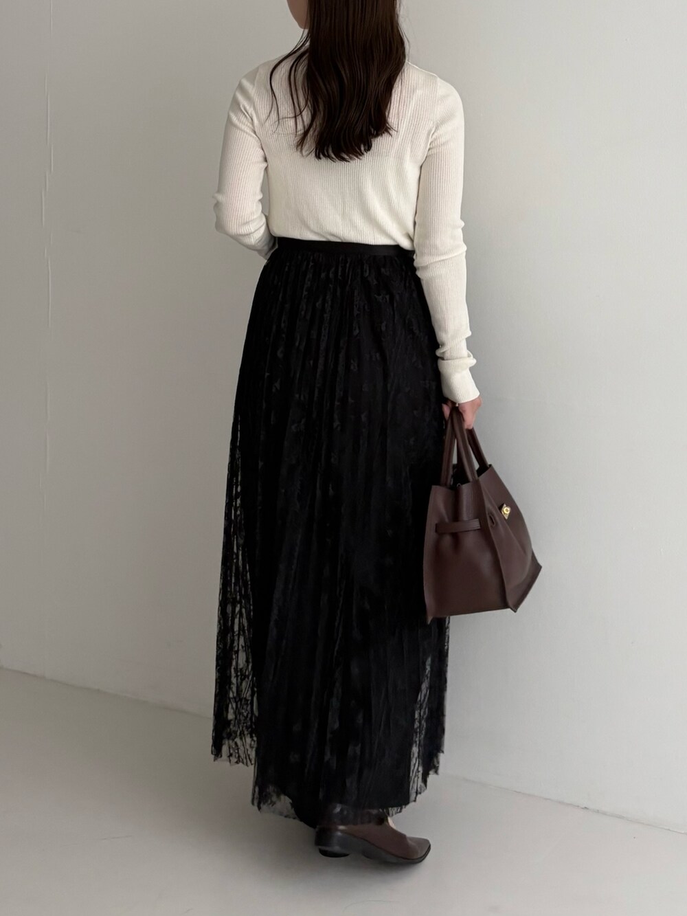 ホワイト系のニット/セーター、ブラック系のスカート、ブラック系のその他パンツを着用したレディースの秋コーディネートの3枚目の写真