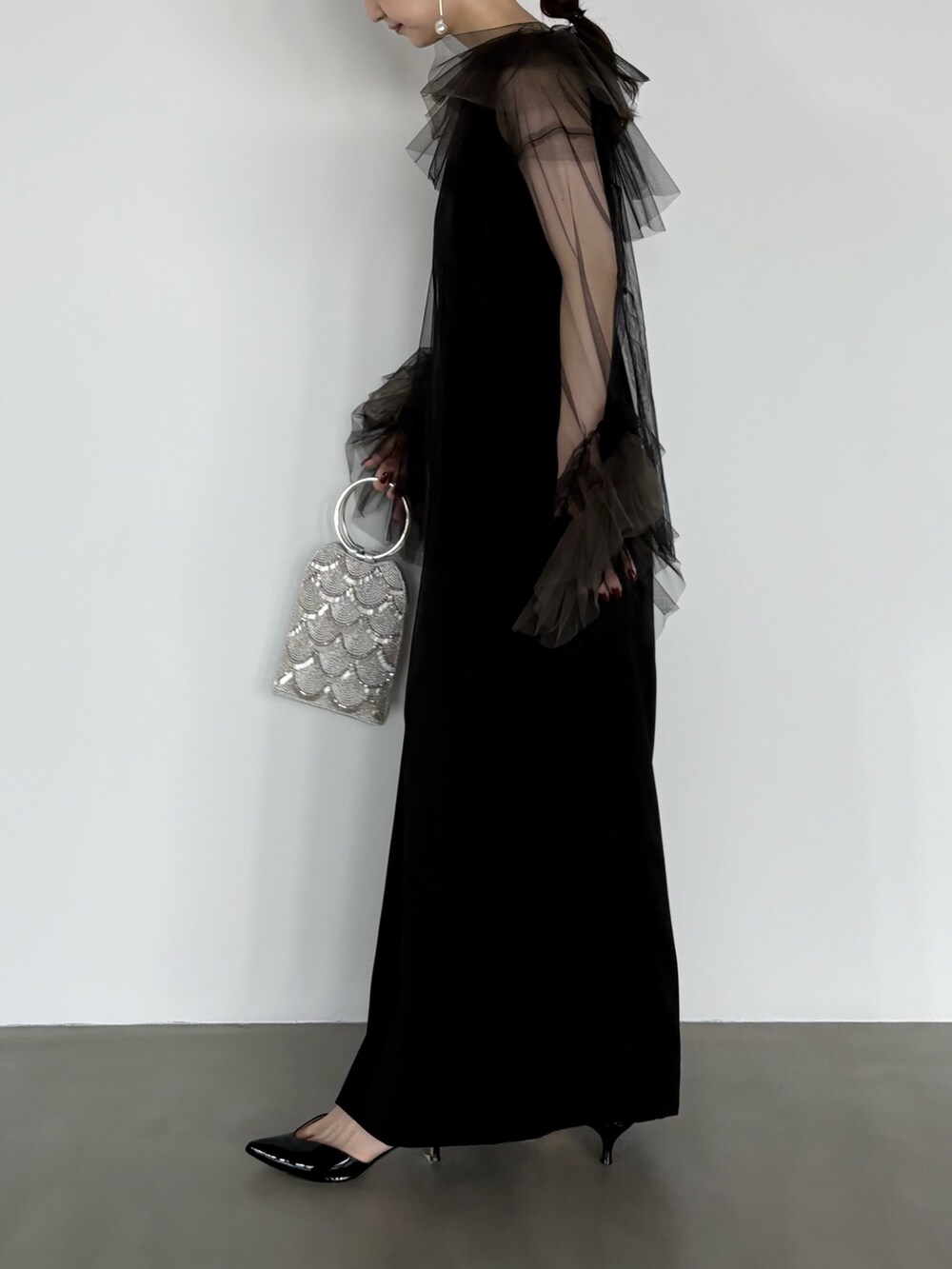 シルバー系のハンドバッグ、ブラック系のワンピースを着用したレディースの秋コーディネートの2枚目の写真