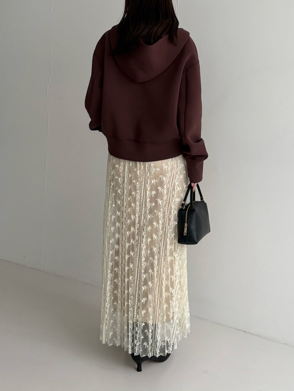 ホワイト系のスカート、ブラック系のブーツ、ブラウン系のパーカーを着用したレディースの秋コーディネートの3枚目の写真